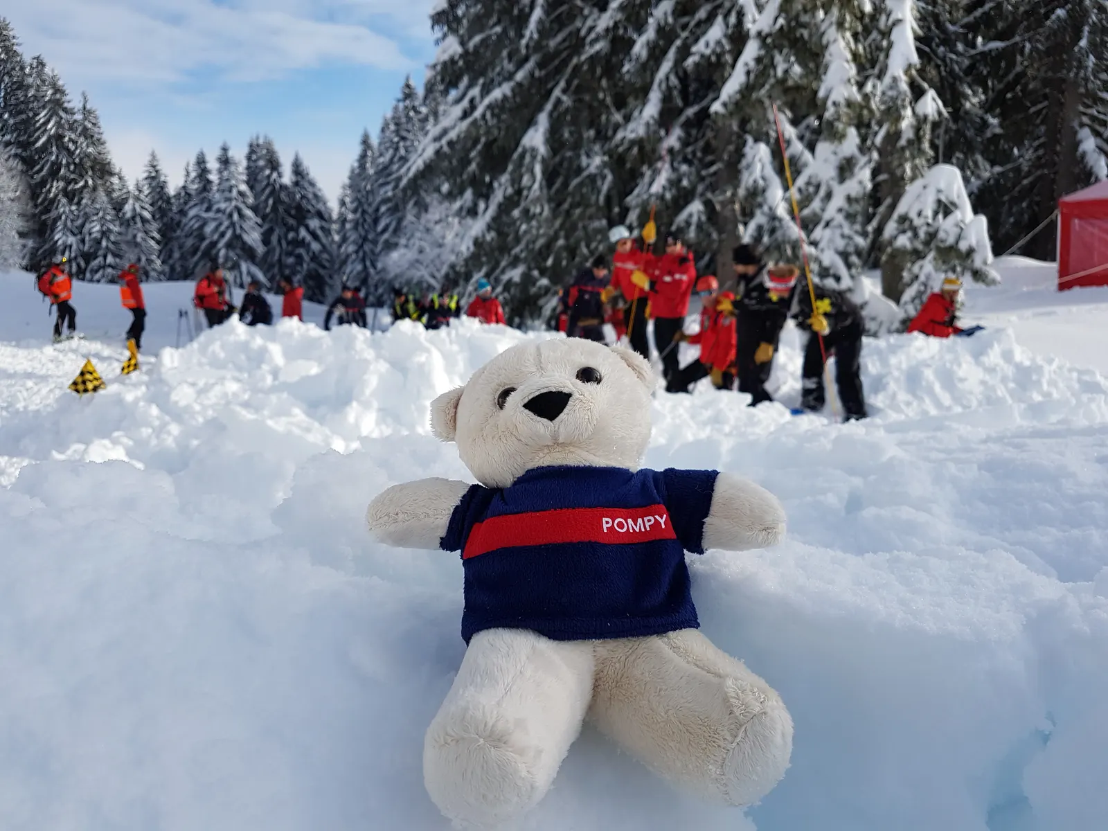 Pompy assis dans la neige devant des skieurs